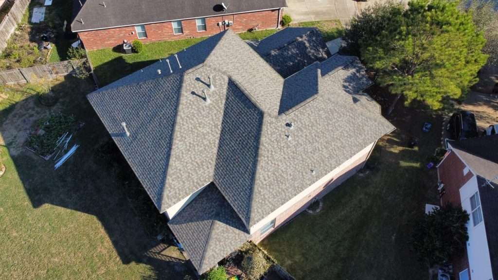 Aerial view of a residential roof showcasing asphalt shingles, highlighting the roof's condition and design relevant to roofing and insurance claims.