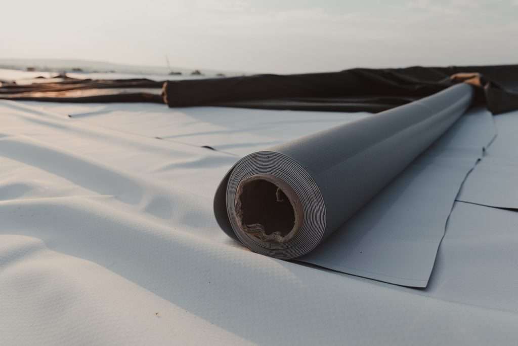 Rolled roofing material on a flat roof installation site, emphasizing the importance of quality roofing for home value and durability.