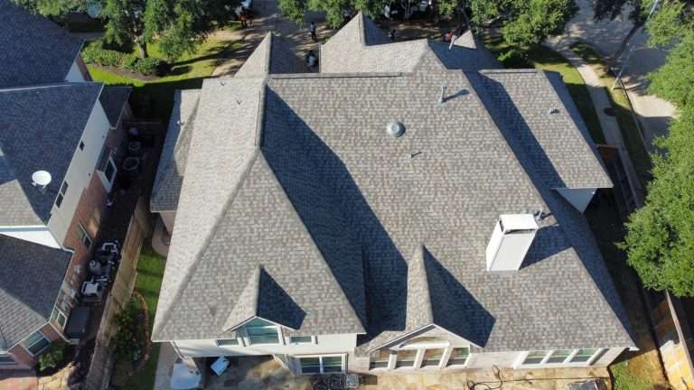 Aerial view of a residential roof showcasing a well-maintained shingle roof design, emphasizing durability and protection against UV damage, relevant to summer roofing care.
