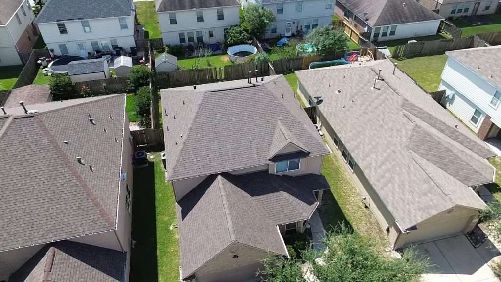 Aerial view of residential homes in Sealy, Texas, showcasing recently installed asphalt roofing, highlighting the quality and durability of roofing services provided by Executive Roofing Team.